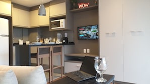 Una cocina moderna con microondas, cafetera y un televisor mostrando la interfaz de Netflix. Hay una computadora portátil sobre una mesa con una copa de vino.