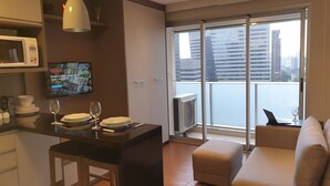 Una cocina moderna con microondas, una mesa de comedor dispuesta con platos y copas de vino, y un ventanal con vistas a la ciudad.