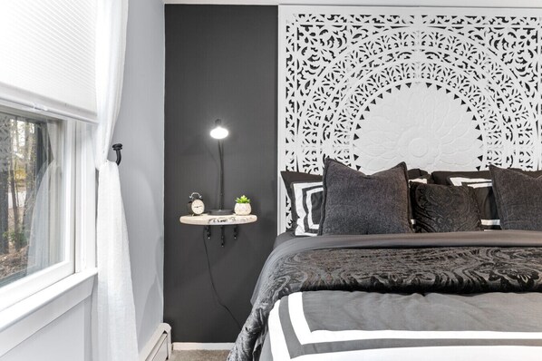 Ein Schlafzimmer mit einem Bett, einer an der Wand befestigten Ablage mit einer Uhr und einer Pflanze sowie einer dekorativen Wandverkleidung.