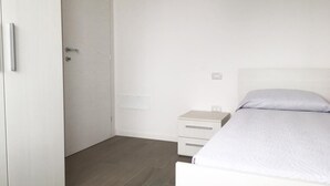 Ein Schlafzimmer mit einem Bett, einem Nachttisch und einer geschlossenen Tür.