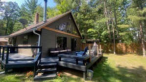 Een chalet met terras, buitenmeubels en schoorsteen.