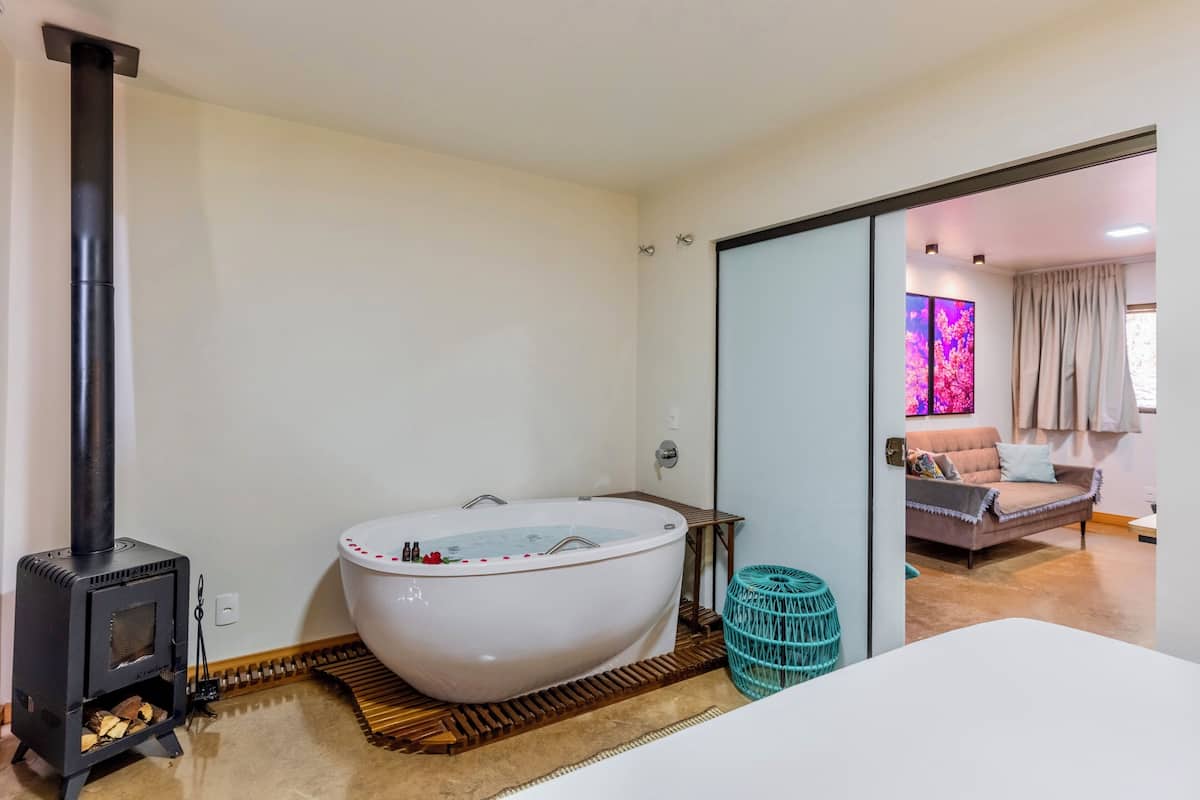 A modern bathroom with a freestanding bathtub, a wood-burning stove, and a glass shower enclosure.