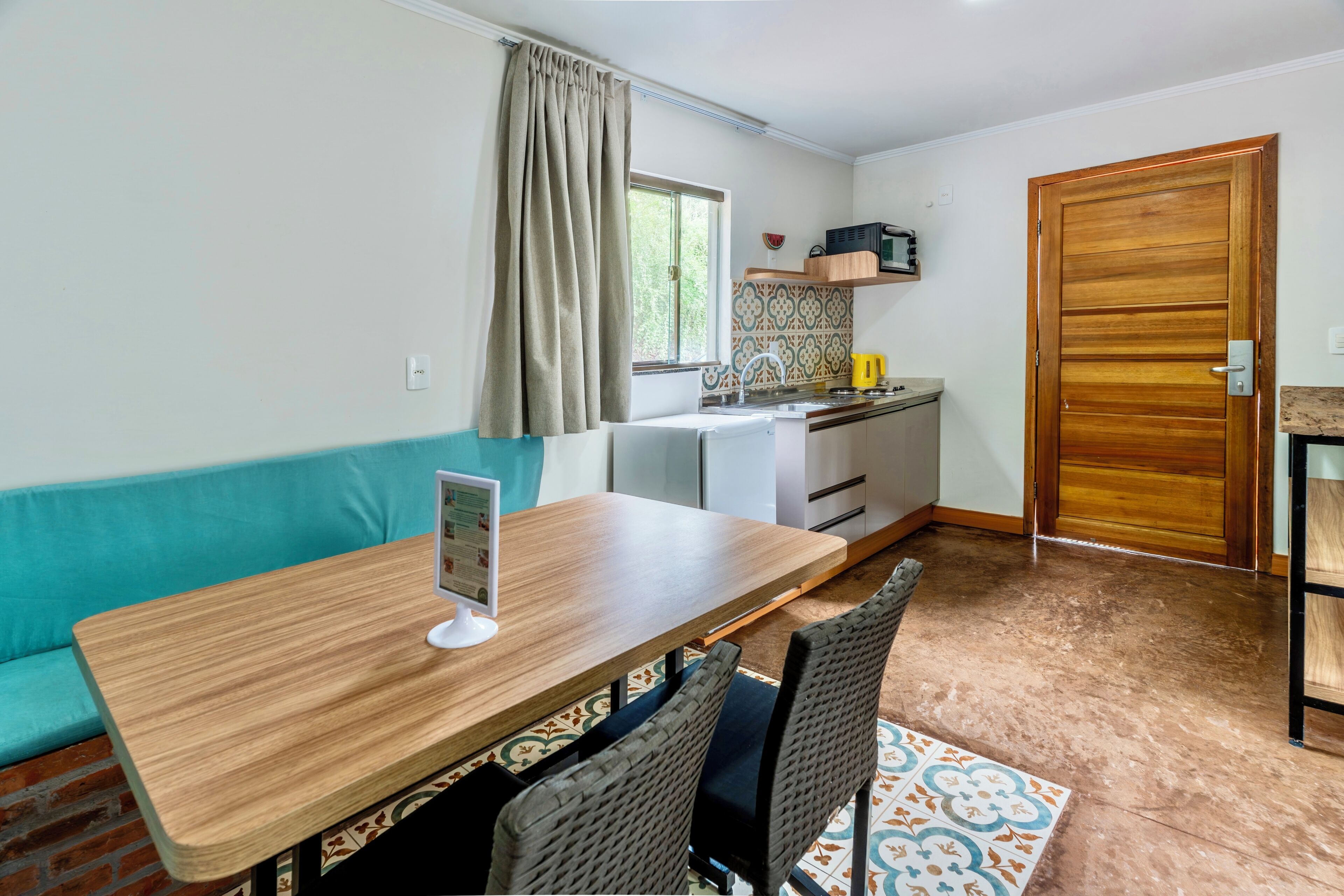 Una cocina compacta con una mesa de comedor, sillas, microondas y una puerta de madera.