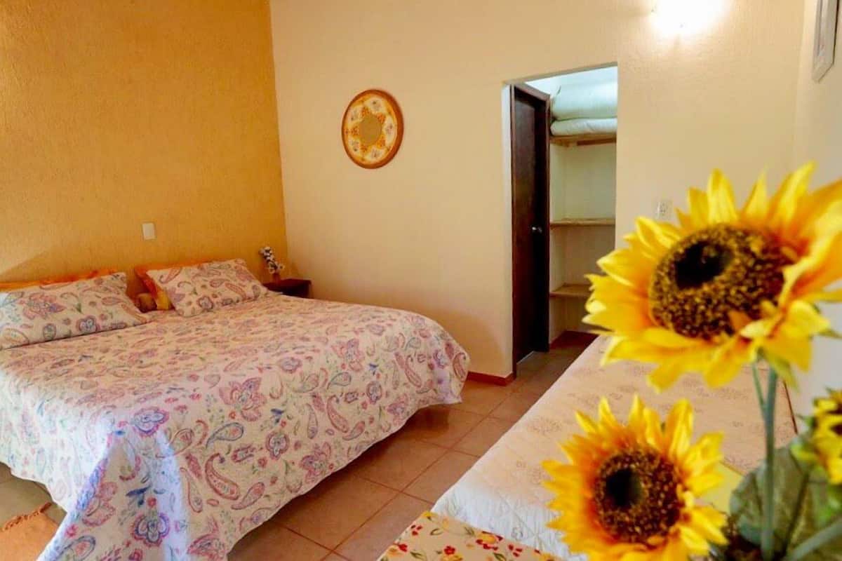 A bedroom with a bed, a nightstand, a wall clock, and a door leading to another room.