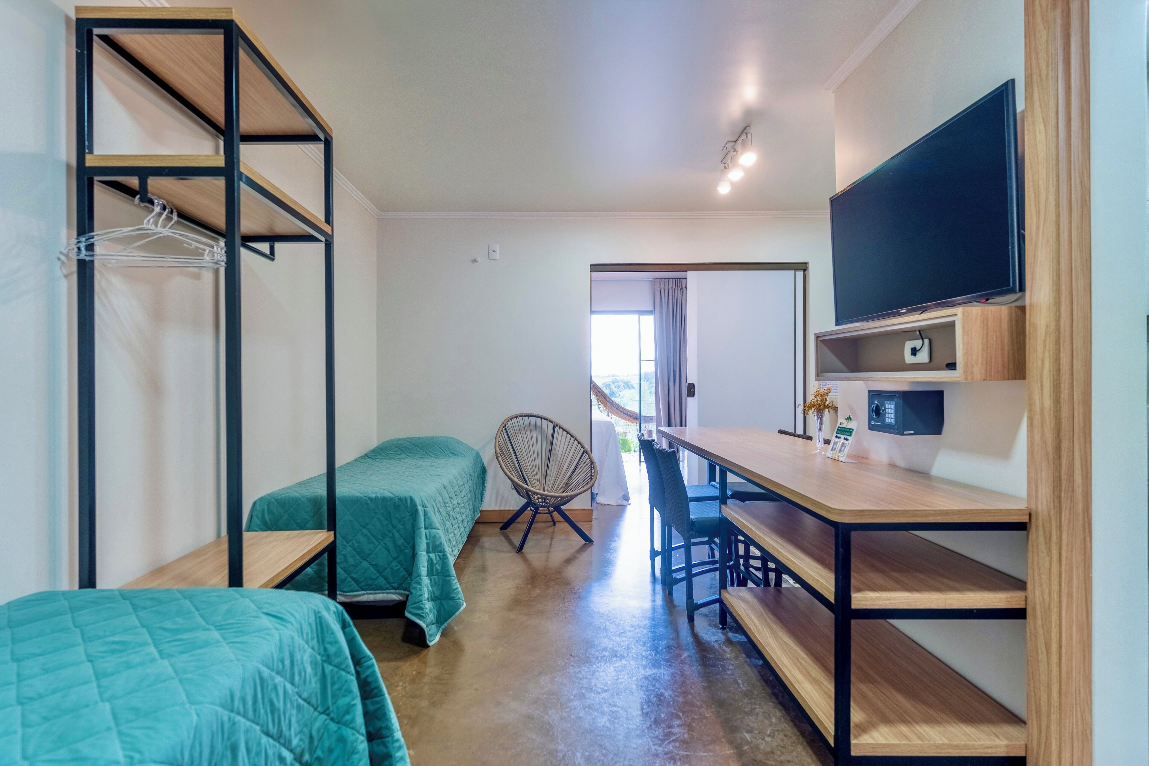 Habitación pequeña con literas, un escritorio, una silla, un televisor y una ventana.