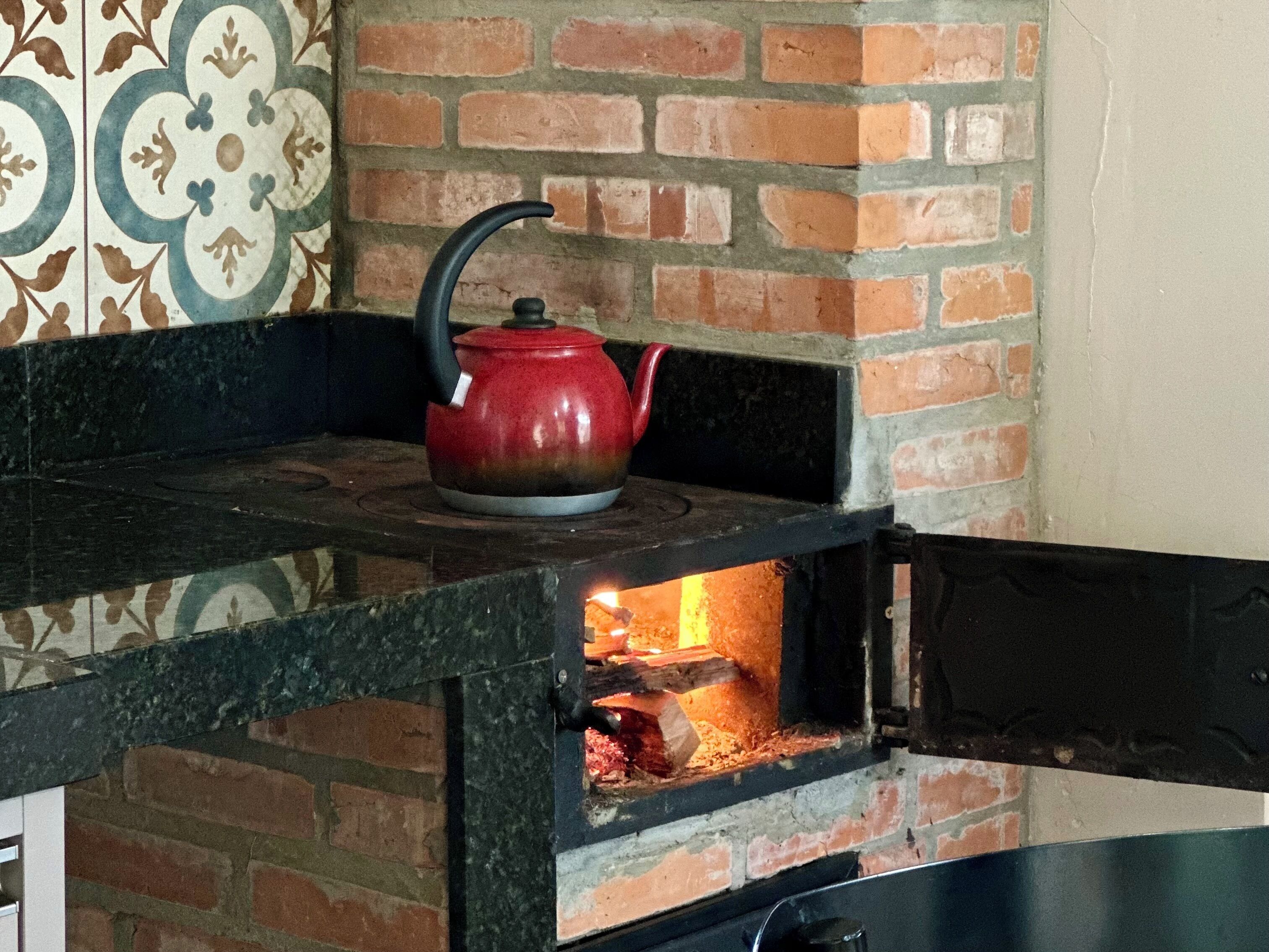 Een bakoven met een rode waterkoker, een zwart aanrecht en een behang met patroon op de achtergrond.
