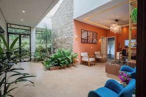 A spacious indoor area with a stone wall, a glass partition, and a seating area with blue chairs.