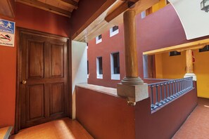 A wooden door with a brass handle, a red wall with a window, and a sign indicating no smoking. - Meson Real Hotel & Suites (Xalapa)