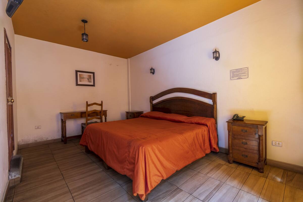 A bedroom with a wooden bed, a desk, and a dresser.