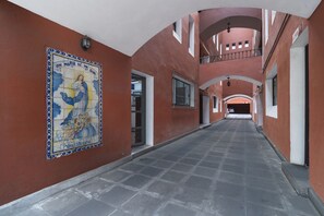 A corridor with a tiled mural, a staircase, and a view into another room. - Meson Real Hotel & Suites (Xalapa)
