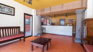 A lobby with a reception desk, wooden benches, a coffee table, and a chandelier. - Meson Real Hotel & Suites (Xalapa)