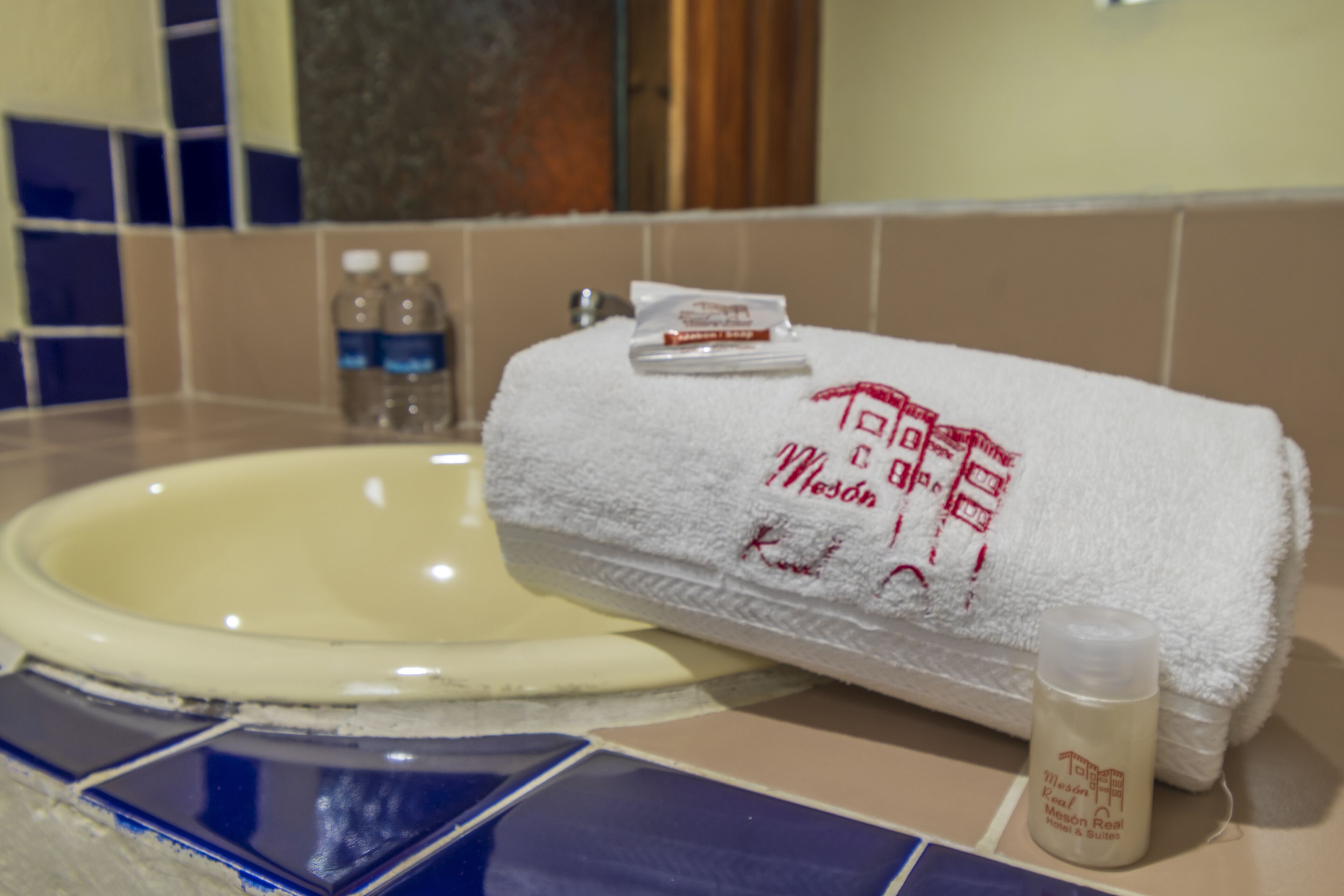 En handfat i badrummet med ett vitt handduk och en flaska lotion på bänkskivan.