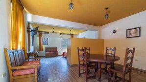 A dining area with a wooden table and chairs, a bench with a cushioned seat, and a ceiling fan. - Meson Real Hotel & Suites (Xalapa)