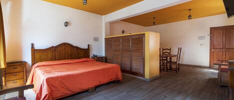 A bedroom with a wooden bed, a wardrobe, a desk, and a chair.