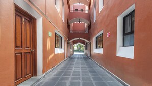 A corridor with a wooden door on the left, a balcony with railings, and a window on the right. - Meson Real Hotel & Suites (Xalapa)