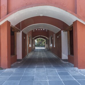 A corridor with a tiled floor, arched ceilings, and red walls. - Meson Real Hotel & Suites (Xalapa)