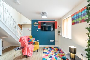 Stylish living area with a staircase, comfortable seating, and a wall-mounted TV.