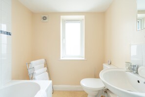 Bathroom features a bathtub, toilet, and sink with a mirror.