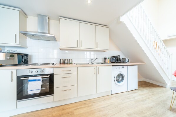 Enjoy cooking in this well-equipped kitchen with a stainless steel range hood, oven, and convenient washing machine.