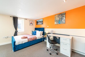 Cozy retreat with a neatly made bed, desk, and artwork on the wall.
