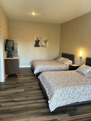 A hotel room with two beds, a flat-screen TV, a small desk, and a wall-mounted artwork. - Newer private Studio in a great location (San Diego)
