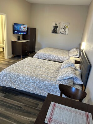 Ett hotellrum med en säng, ett skrivbord, en tv och konstverk på väggen.