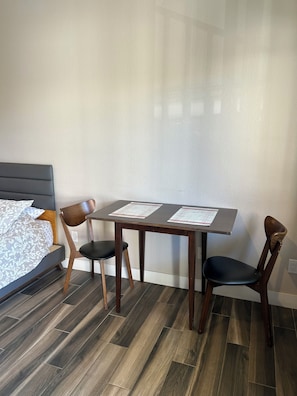 A bedroom with a bed, two chairs, a table, and a wooden floor. - Newer private Studio in a great location (San Diego)