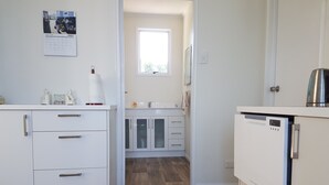 A modern kitchen with white cabinetry, a built-in oven, and a window providing natural light.