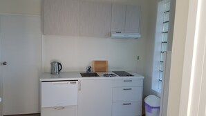 A compact kitchenette with a built-in oven, a sink, and a small countertop.