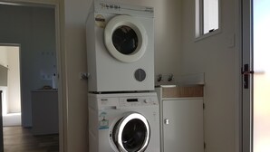 A laundry room with stacked washing machines and a dryer.