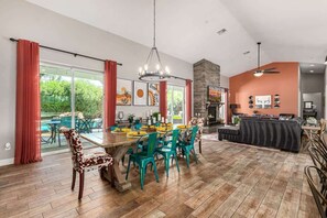 Un comedor amplio con una gran mesa y sillas, chimenea y vistas al exterior.