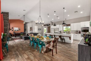 Large kitchen featuring stainless steel appliances, basic cooking essentials, 5 person breakfast bar seating, and a formal dining table for 8.