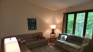 A living room with a brown couch, a patterned sofa, a lamp, and a sign that says "JUMP in the LAKE".