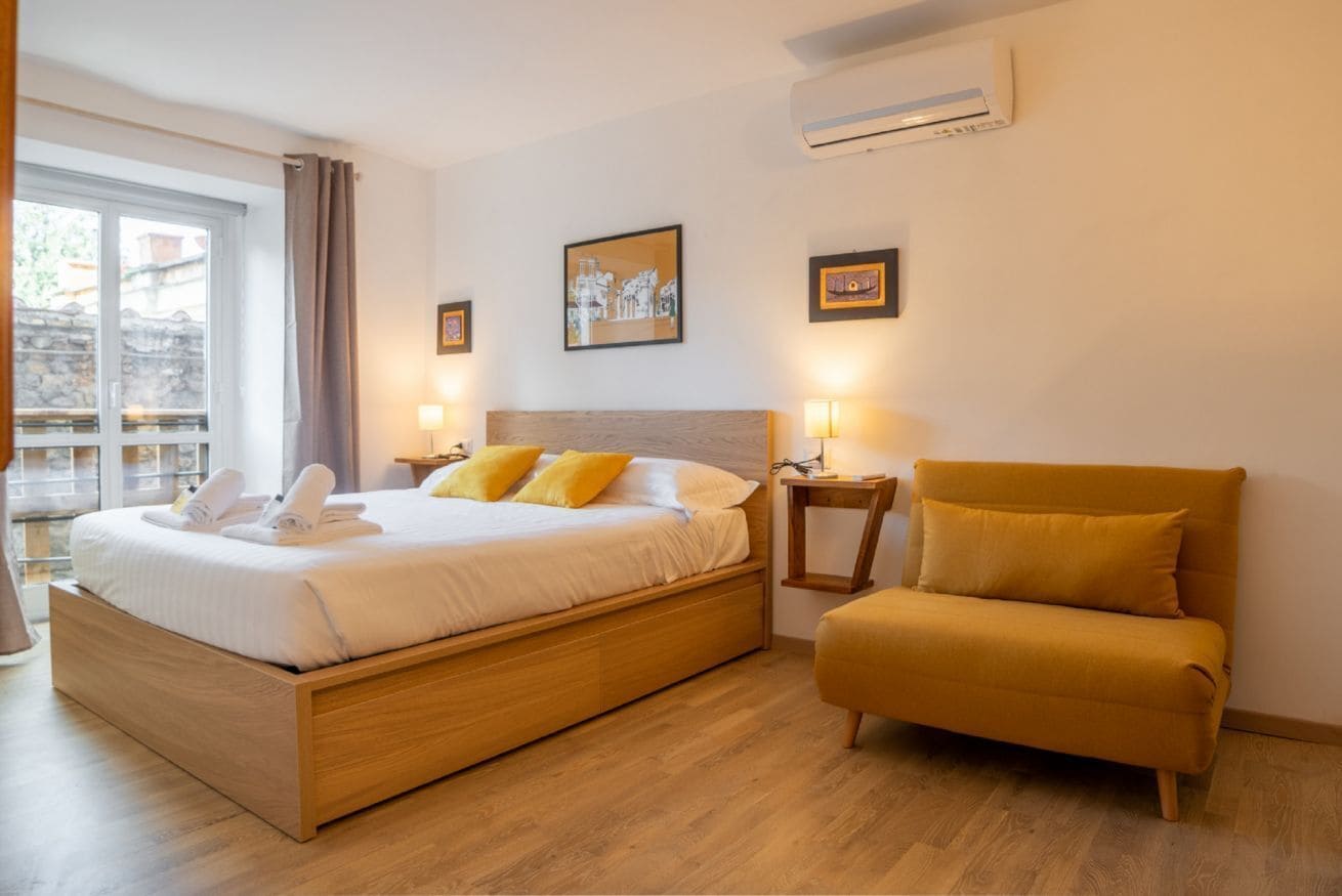 Una camera d'albergo con un letto di legno, un divano, un tavolino e un quadro appeso al muro.