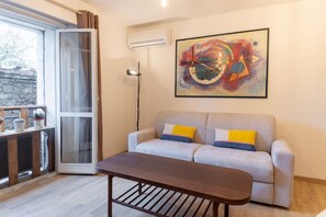 A living room with a sofa, a coffee table, a painting, and a sliding glass door.
