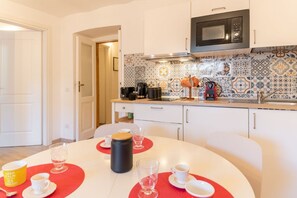 A modern kitchen with white cabinets, a microwave, and a tiled backsplash. - Domus Domi Quirinale (Via delle Quattro Fontane) (Roma)