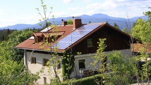 Una casa con techo inclinado, paneles solares y vistas a montañas al fondo.