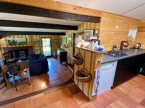 A wooden interior with a kitchen area, dining space, and a living room with a sofa and chairs. - Pool house in idyllic location A3695 (Lège-Cap-Ferret)