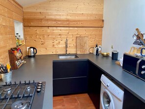 A compact kitchen with a gas stove, a sink, and a washing machine.