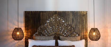 A bed with a decorative headboard, two hanging lamps, and a striped rug.