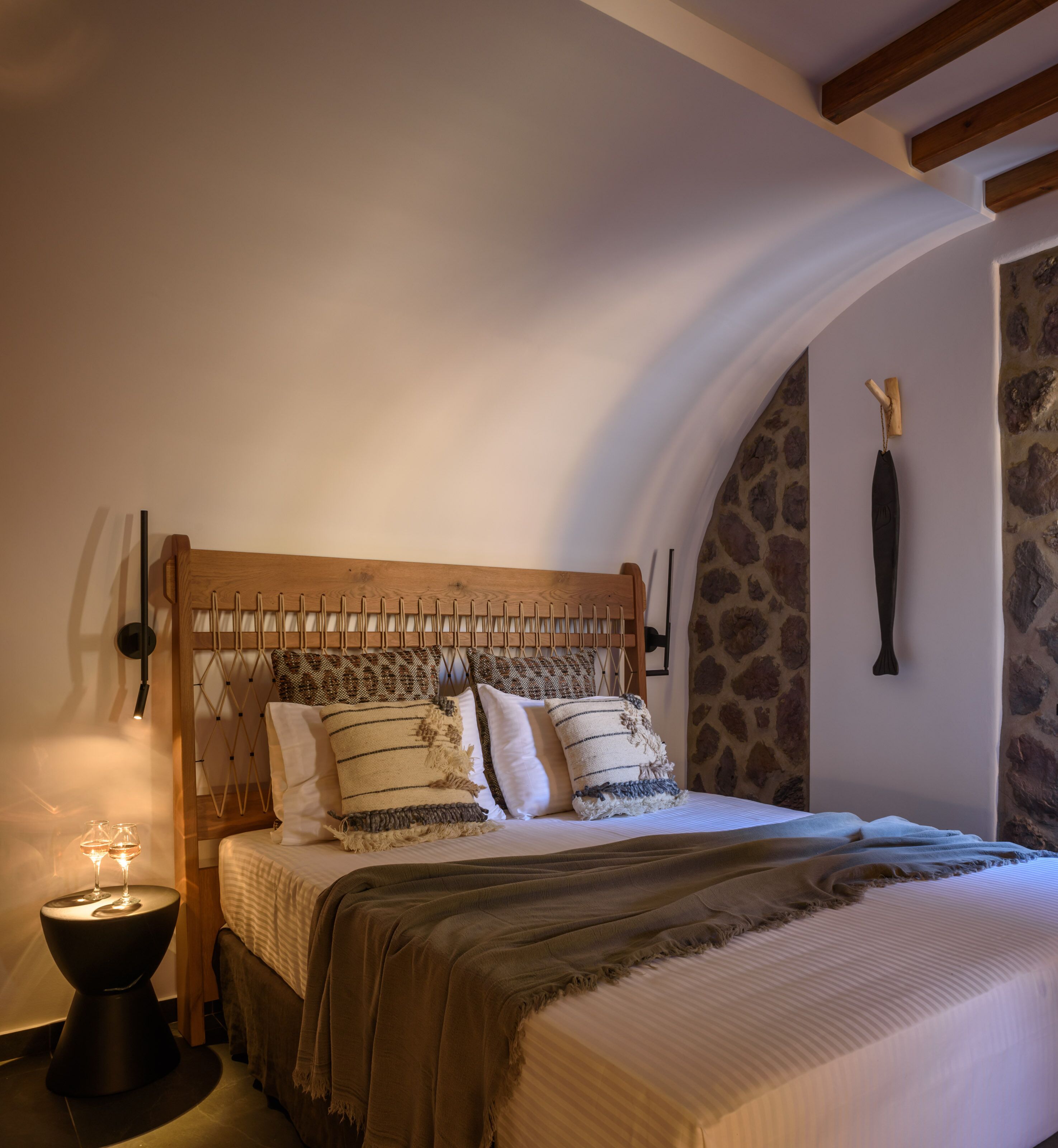 Una camera da letto con una testiera in legno, un muro in pietra e un letto con biancheria a righe.