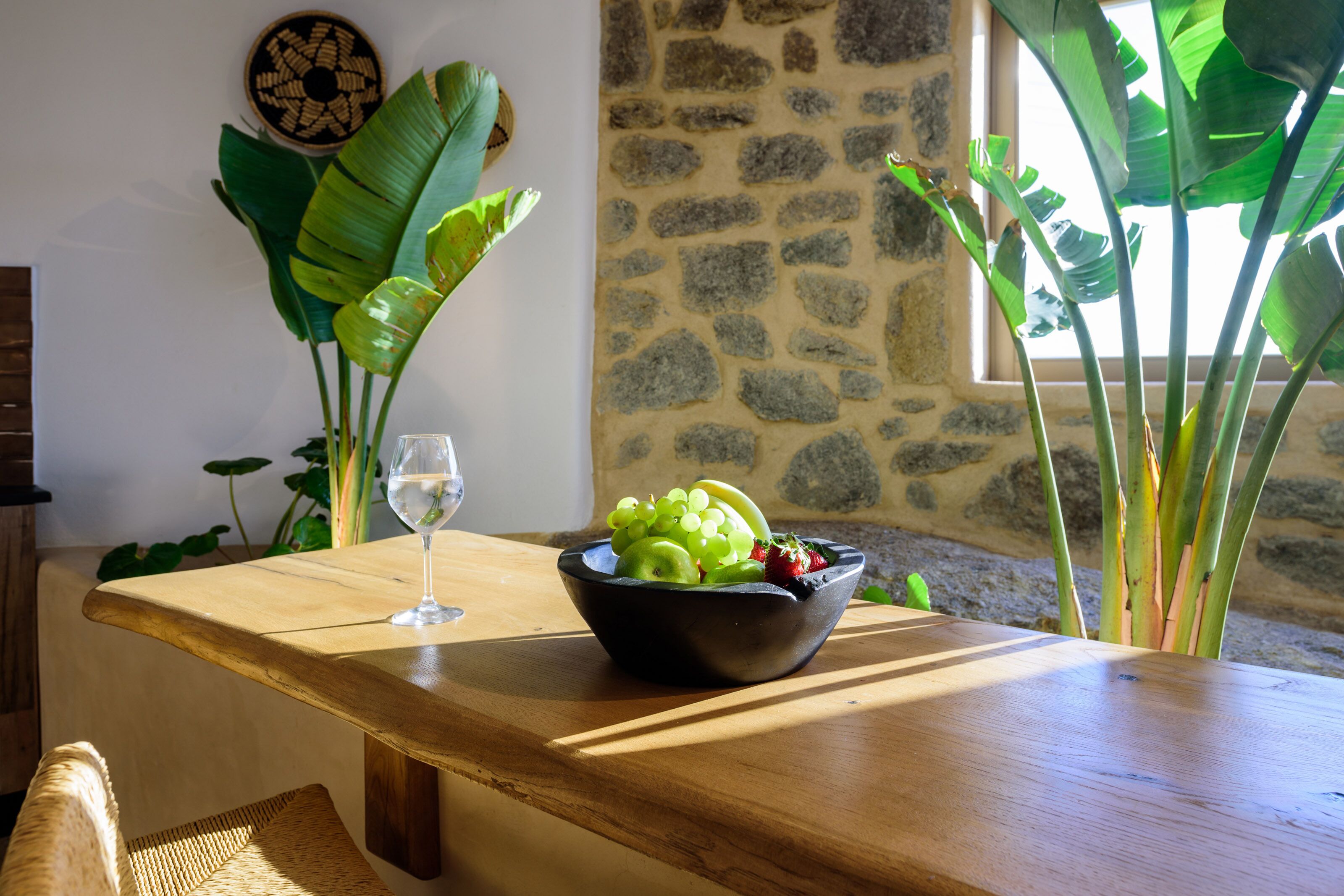 Une table en bois avec un saladier de fruits et un verre de vin blanc.