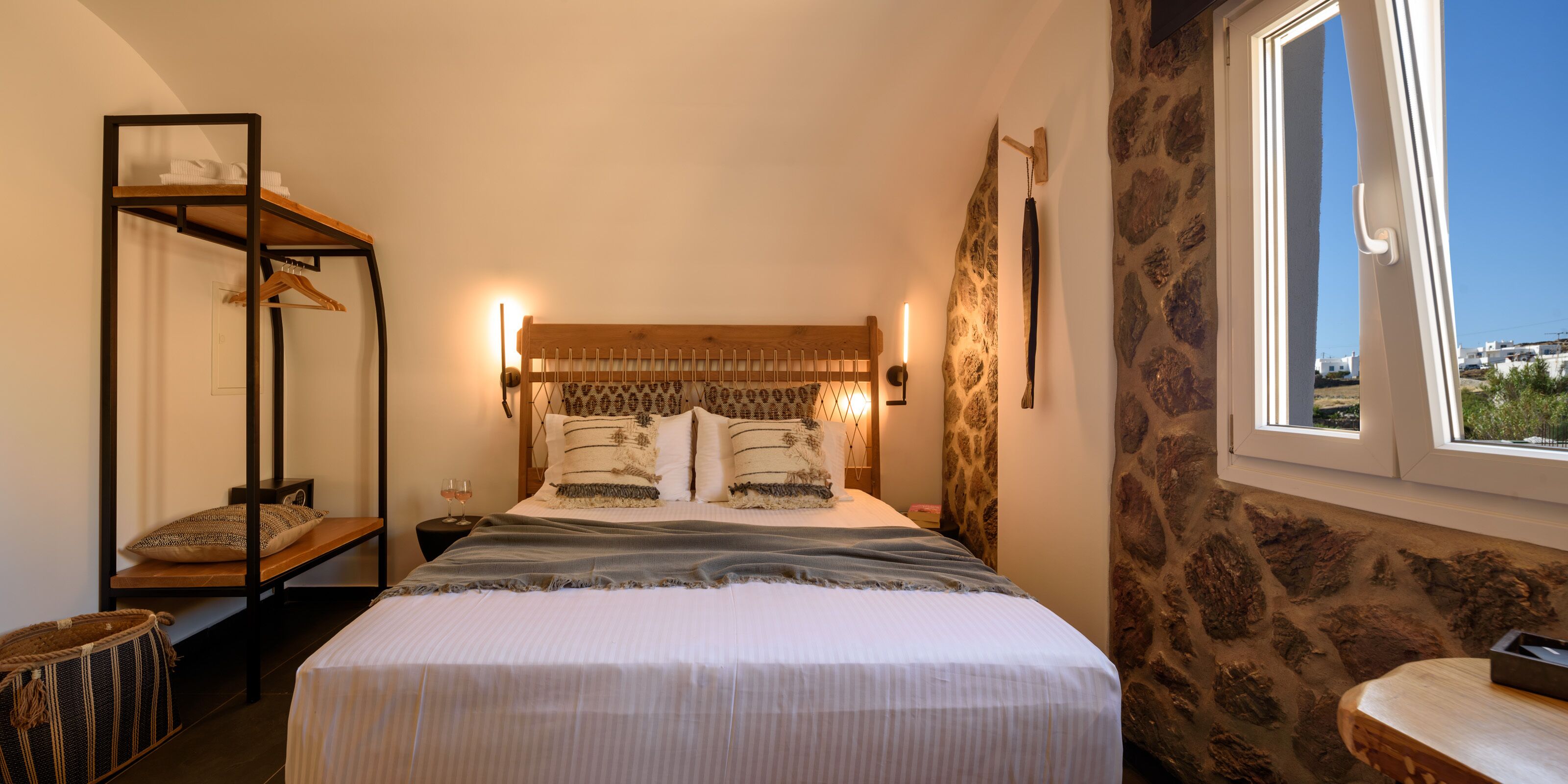 Un dormitorio con cama, mesita de noche de madera, armario colgado y pared de piedra.