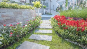 Un sendero en un jardín con piedras que conducen a un edificio blanco con balcón.