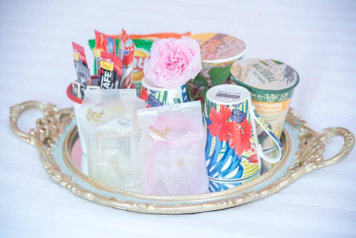 A tray with various packaged items, a pink flower, and a container of yogurt.