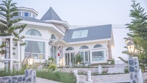 Una casa grande y moderna con una torre destacada y numerosas ventanas.