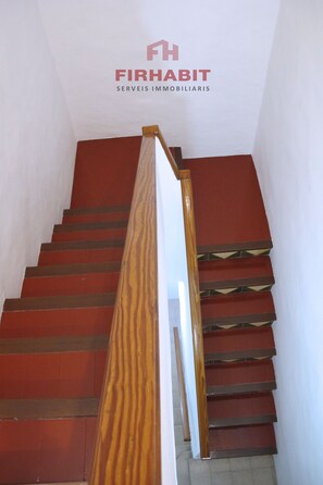 Staircase with a handrail and red steps, set against a white backdrop.