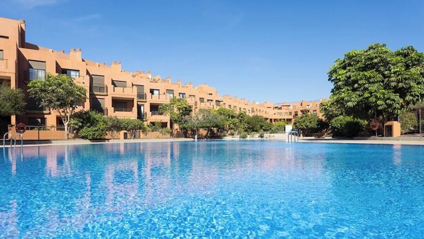 A swimming pool with clear blue water, surrounded by buildings with a uniform architectural style. - Home2Book La Tejita Beach and Pool (Granadilla)