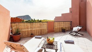 A rooftop terrace with lounge chairs, a table with fruit, and a view of a mountain. - Home2Book La Tejita Beach and Pool (Granadilla)