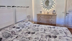 Une chambre à coucher avec un lit, une commode, un miroir et une porte.